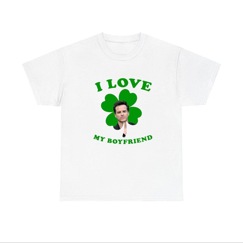 May include: White t-shirt with a green four-leaf clover design. The clover has a man's face in the center. The text "I LOVE MY BOYFRIEND" is printed below the clover.