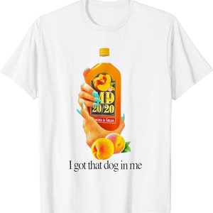 以下が含まれることがあります： 桃の風味のMD 20/20ワインのボトルを持った手のグラフィックがプリントされた白いTシャツ。ボトルはオレンジ色で、ラベルに桃が描かれています。グラフィックの下には「I got that dog in me」というテキストがプリントされています。