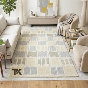 以下が含まれることがあります： 黒い持ち手と「But First, Coffee」の太字の黒い文字が入った白いセラミックマグ。マグは木製の表面に置かれています。マグの高さは約10cmです。