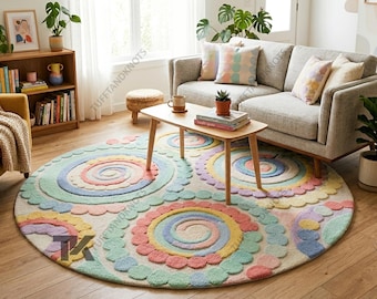May include: A round, colorful rug with a whimsical design. The rug features large, spiral-shaped patterns in pastel colors like pink, blue, yellow, and green. The rug is placed in a living room setting with a sofa, coffee table, and plants.