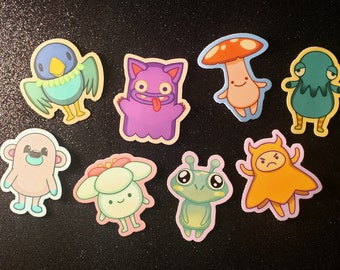 May include: A set of nine colorful cartoon character stickers. The stickers feature a variety of characters, including a bird, a mushroom, a ghost, a flower, a frog, a monster, and a bear. The stickers are perfect for adding a touch of whimsy to any project.