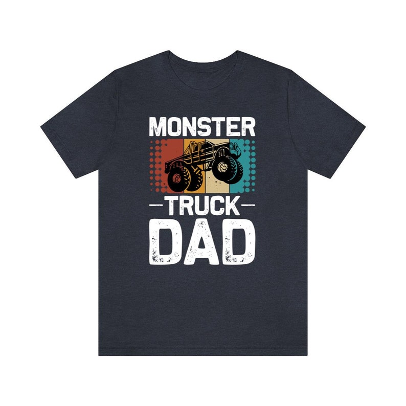 May include: A dark blue t-shirt with a vintage-style graphic of a monster truck. The text "Monster Truck Dad" is printed in white on the shirt.