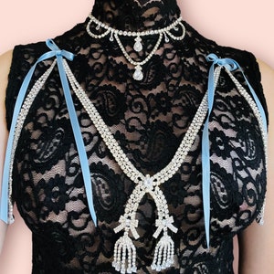 May include: A black lace top with a rhinestone choker and a rhinestone necklace with two dangling tassels. The necklace has blue ribbon ties.