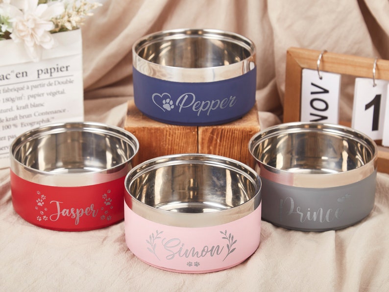K&ouml;nnte beinhalten: Vier personalisierte Edelstahl-Napf f&uuml;r Haustiere mit den Namen Pepper, Jasper, Simon und Prince. Die N&auml;pfe sind in Blau, Rot, Rosa und Grau.