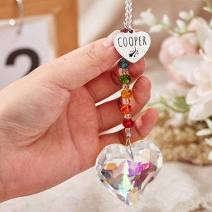 Puede incluir: Un atrapasol de cristal en forma de coraz&oacute;n con cuentas de arco&iacute;ris y un dije de coraz&oacute;n plateado con el nombre "COOPER" grabado.