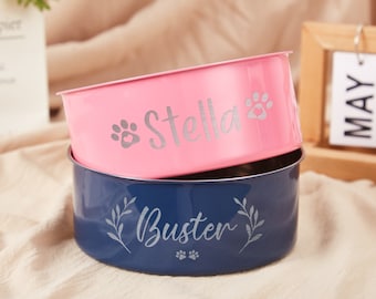 May include: Two personalized pet bowls, one pink with the name "Stella" and a paw print, and one blue with the name "Buster" and a paw print and leaves.