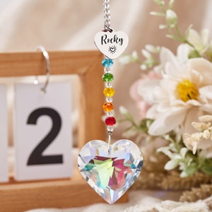Puede incluir: Un atrapasol de cristal arco&iacute;ris con un cristal en forma de coraz&oacute;n en la parte inferior. El atrapasol tiene un dije de coraz&oacute;n plateado con la palabra "Rocky" y un peque&ntilde;o s&iacute;mbolo de sol grabado en &eacute;l.