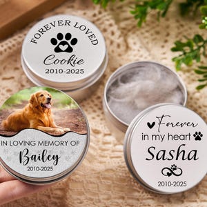 May include: Silver pet memorial tins with personalized text and paw print designs. One tin features a photo of a golden retriever. Text includes "Forever Loved," "In Loving Memory," and pet names with dates.