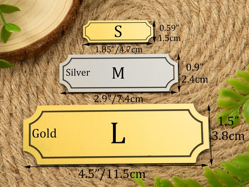 Peut inclure: Trois plaques de nom en m&eacute;tal de couleur or, argent et or avec des bordures noires et des coins arrondis. Les plaques de nom sont &eacute;tiquet&eacute;es "S", "M" et "L" et ont des dimensions en pouces et en centim&egrave;tres.