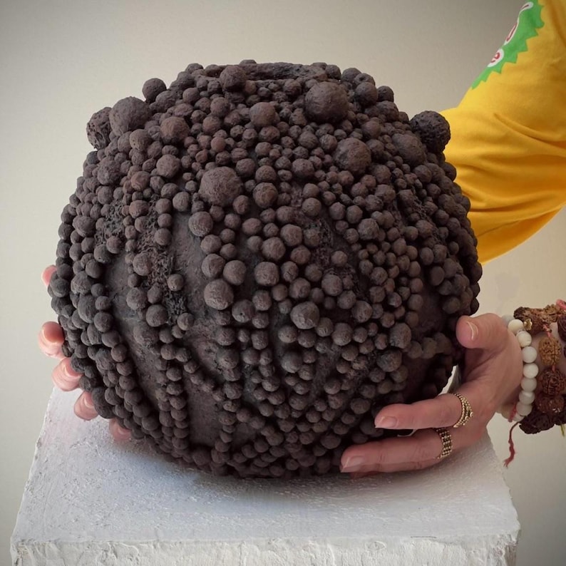 Textured brown sphere sculpture acting as a wabi-sabi decorative vase.