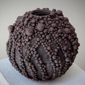 Organic paper clay vase featuring layered spherical forms and earthy mineral texture.