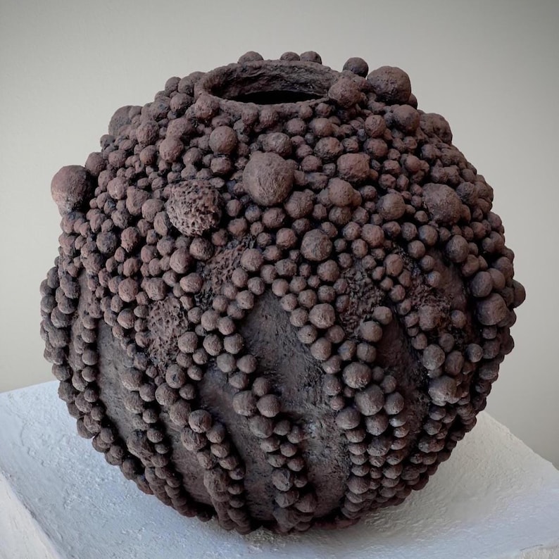 Organic paper clay vase featuring layered spherical forms and earthy mineral texture.