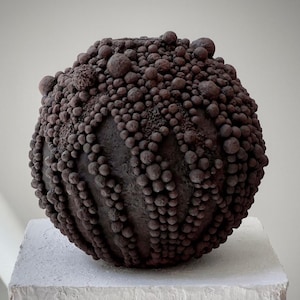 Sculptural wabi-sabi vase in deep brown tones with clustered spherical texture.