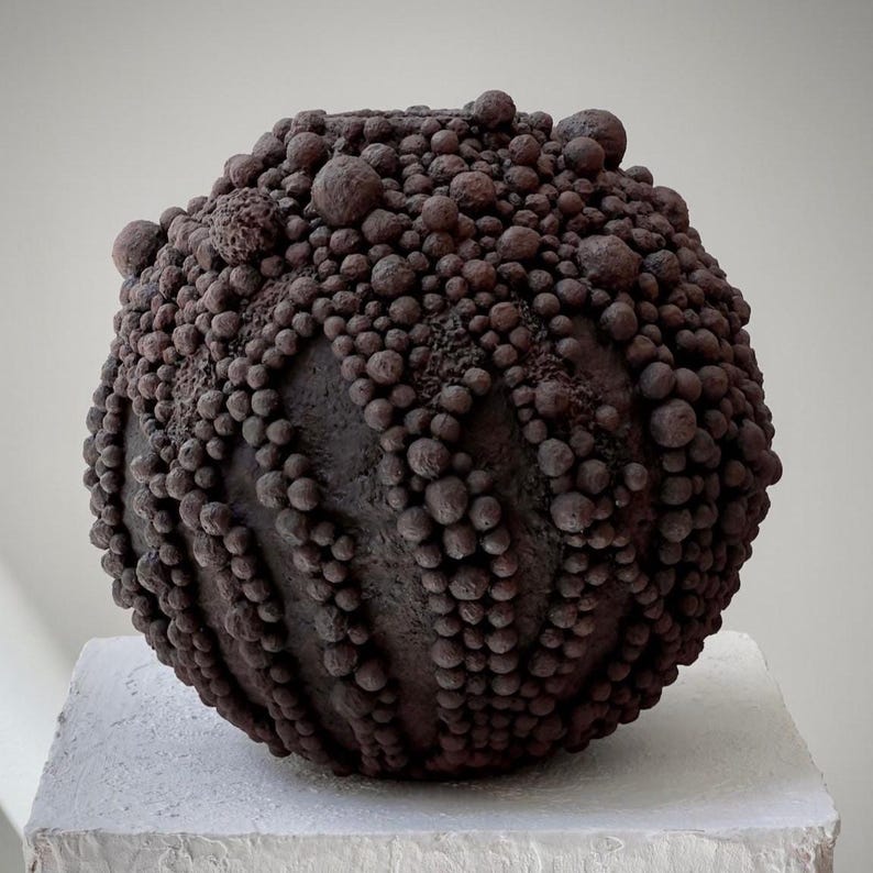 Sculptural wabi-sabi vase in deep brown tones with clustered spherical texture.