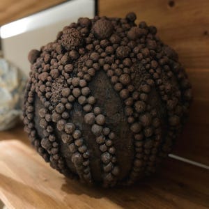 Handcrafted wabi-sabi vase with raw clustered texture and natural clay pigments.