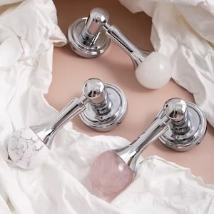 Puede incluir: Tres pomos de puerta plateados con diferentes mangos de piedra de colores. Los mangos son de mármol blanco, cuarzo rosa y blanco con vetas grises.