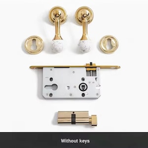 May include: A set of gold door handles with white marble accents, a silver door lock, and a gold cylinder lock. The image text reads "Without keys".