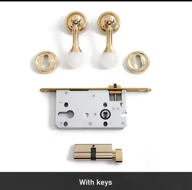 May include: A gold door handle set with a keyhole cover, a door lock, and a cylinder lock. The set includes two door handles with round knobs and a white center. The text "With keys" is visible at the bottom of the image.