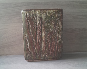 Peut inclure: Un vase rectangulaire en céramique avec un glaçage texturé brun et vert. Le vase a un motif en relief d'une fleur au centre.