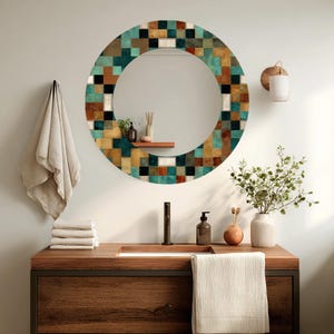 May include: A round bathroom mirror with a mosaic tile border in shades of teal, brown, black, and white. The mirror hangs above a wooden vanity with a sink, faucet, and accessories.