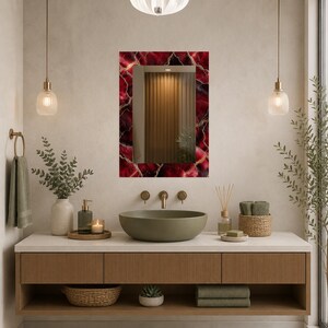 May include: A rectangular mirror with a red and gold patterned frame hangs above a bathroom vanity. The vanity has a wooden cabinet with a light-colored countertop. A green vessel sink and gold fixtures are visible.