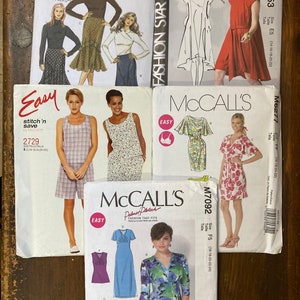 May include: A collection of sewing patterns for various clothing styles. The patterns are from Vogue, McCall's, and Fashion Star. The patterns include a variety of sizes and styles, including dresses, tops, and skirts.