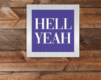 May include: A bedroom with a wooden headboard featuring the text "HELL YEAH" in a white frame. The bed has a white and gray patterned duvet and pillows. Two black pendant lights hang on either side of the bed.