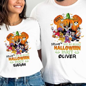 May include: White t-shirts with a Mickey Mouse Halloween design. The shirts feature a pumpkin with Mickey Mouse and friends inside. The text on the shirts reads "Mickey's Not So Scary Halloween Party" with a personalized name below. The year 2024 is also included on the shirts.