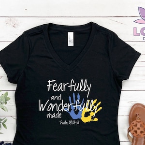 May include: Black v-neck t-shirt with the text "Fearfully and Wonderfully Made" and a pair of blue and yellow handprints. The text "Psalm 139:13-14" is also included on the shirt.