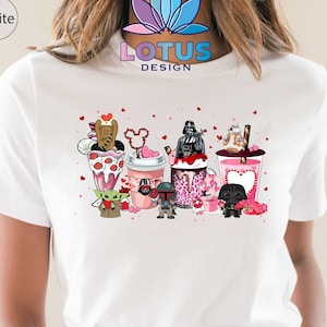 May include: White t-shirt with a graphic of Star Wars characters enjoying Valentine's Day themed treats. The characters include Darth Vader, Yoda, Chewbacca, and others. The text "LOTUS DESIGN" is printed on the shirt.