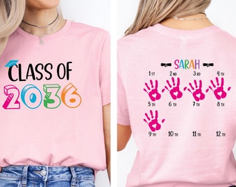 May include: Pink t-shirt with the text "CLASS OF 2036" on the front and the text "SARAH" and a series of pink handprints with numbers 1st through 12th on the back.