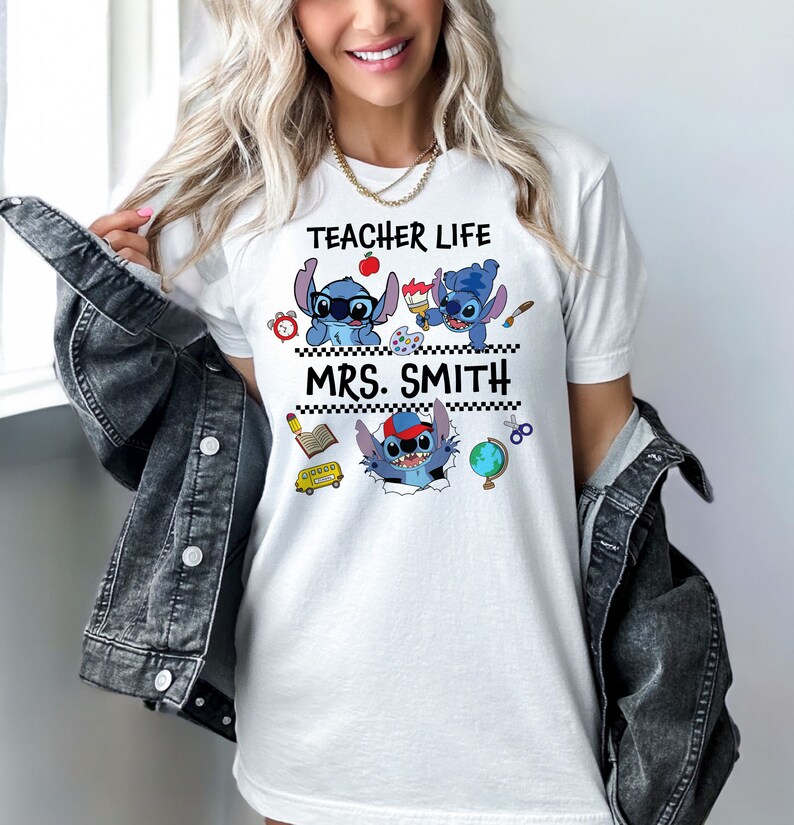 May include: White t-shirt with a blue Stitch character design. The shirt says "Teacher Life" and "Mrs. Smith".