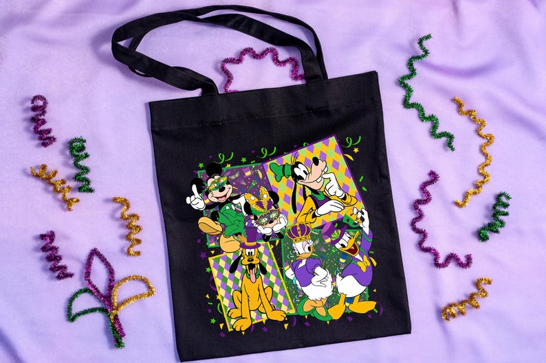 Puede incluir: Bolso tote negro con un dise&ntilde;o colorido de personajes de Disney con atuendos de Mardi Gras. Mickey, Minnie, Goofy, Pluto, Donald y Daisy Duck est&aacute;n representados. Serpentinas decorativas moradas, verdes y doradas rodean el bolso.