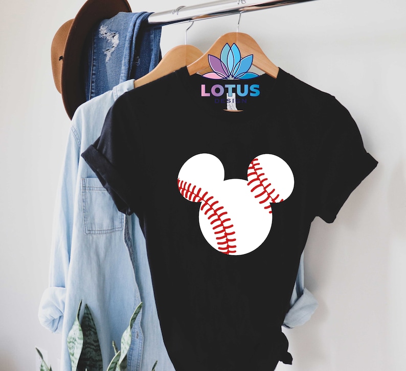 May include: Black t-shirt with a white baseball graphic in the shape of Mickey Mouse ears. The text "LOTUS DESIGN" is printed on the shirt.