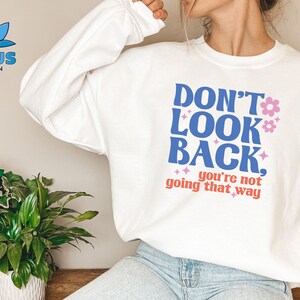 May include: White sweatshirt with a blue and pink graphic that says "Don't Look Back, you're not going that way".