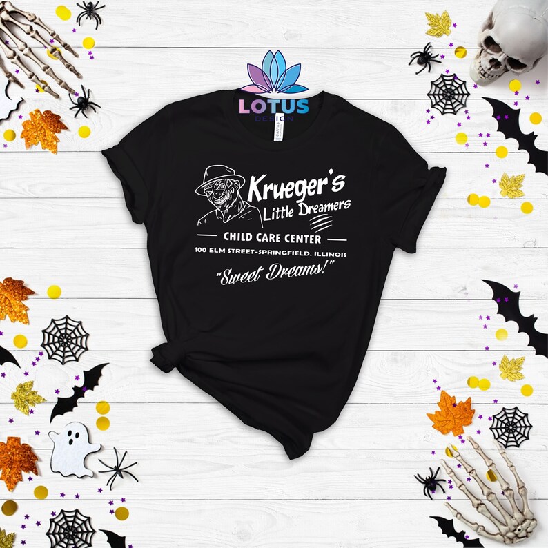 May include: Black t-shirt with a white graphic of Freddy Krueger's "Krueger's Little Dreamers" child care center. The text reads "100 Elm Street-Springfield, Illinois" and "Sweet Dreams!"
