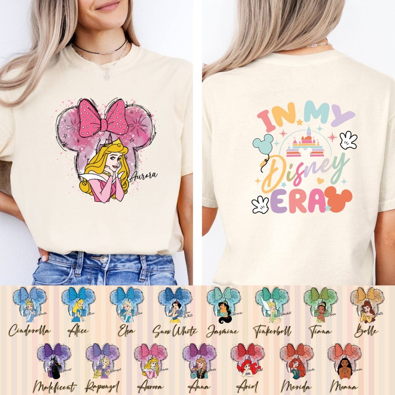 Puede incluir: Una camiseta blanca con un dise&ntilde;o de orejas de Mickey Mouse rosa y blanco con una princesa de Disney. La parte posterior de la camiseta tiene un gr&aacute;fico colorido que dice "In My Disney Era".