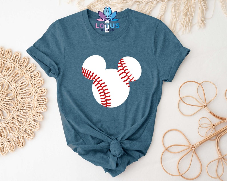 May include: A teal blue t-shirt with a white baseball-shaped Mickey Mouse head graphic. The baseball has red stitching.