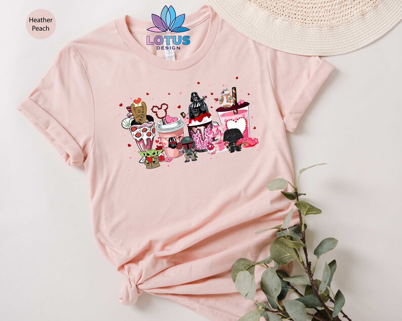 May include: A pink t-shirt with a graphic of Star Wars characters holding Valentine's Day themed drinks. The text "LOTUS DESIGN" is printed on the shirt.