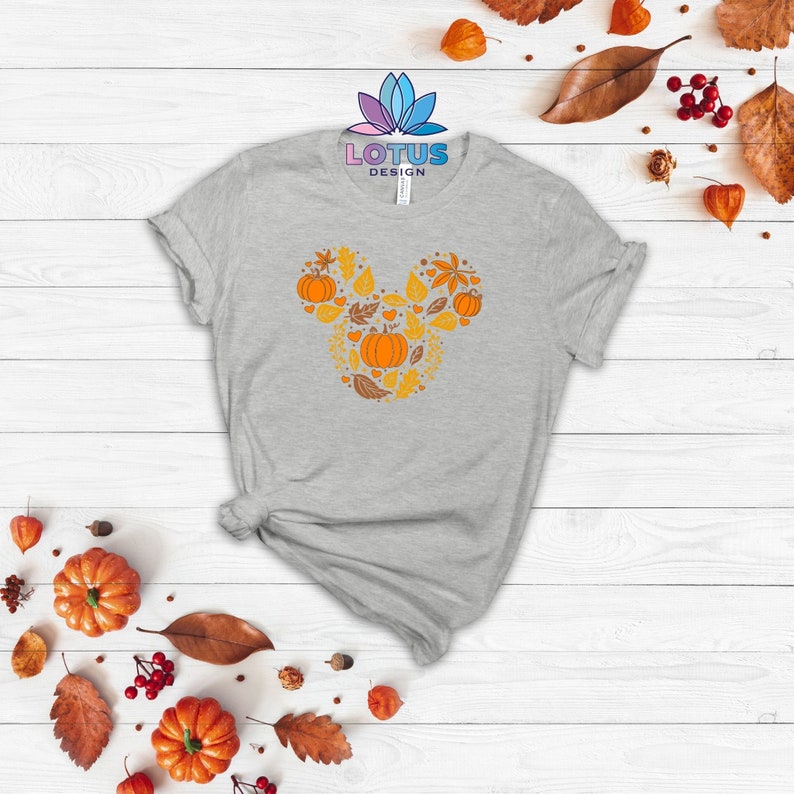 May include: A gray t-shirt with a fall-themed Mickey Mouse design featuring pumpkins, leaves, and hearts. The design is in shades of orange and yellow.