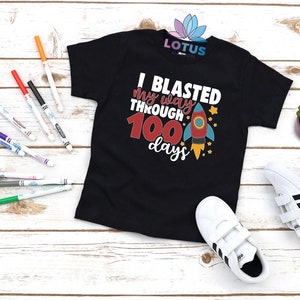 May include: Black t-shirt with a rocket ship graphic and the text "I blasted my way through 100 days".