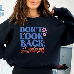 May include: Black sweatshirt with the text "Don't Look Back, you're not going that way" in a retro font with pink flowers and glitter accents.