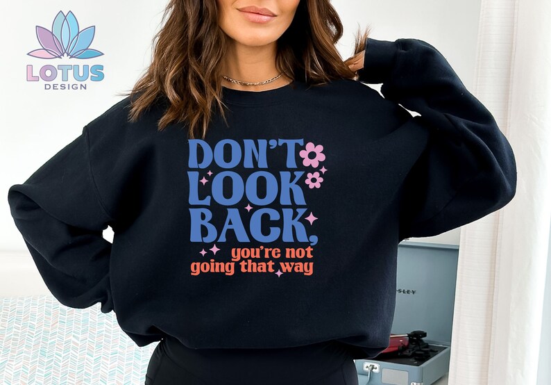 May include: Black sweatshirt with the text "Don't Look Back, you're not going that way" in a retro font with pink flowers and glitter accents.