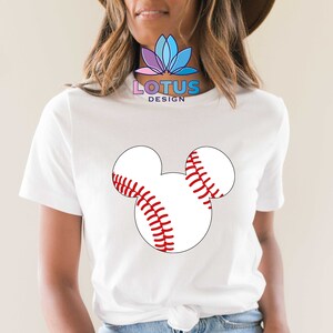 May include: White t-shirt with a red and white baseball Mickey Mouse design. The shirt has the text "LOTUS DESIGN" on the front.