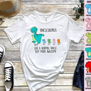 Op de afbeelding: Wit T-shirt met een cartoon dinosaurusafbeelding en de tekst "UNCLESAURUS". Het shirt heeft ook kleinere dinosaurusontwerpen en de zin "LIKE A NORMAL UNCLE, BUT MORE AWESOME".