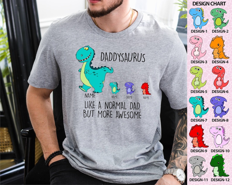 Op de afbeelding: Een grijs t-shirt met een dinosaurusontwerp. De tekst luidt "DADDYSAURUS" en "LIKE A NORMAL DAD, BUT MORE AWESOME." Het ontwerp bevat een grote turquoise dinosaurus en kleinere dinosaurussen. Een ontwerptabel met 12 dinosaurusontwerpen staat rechts.
