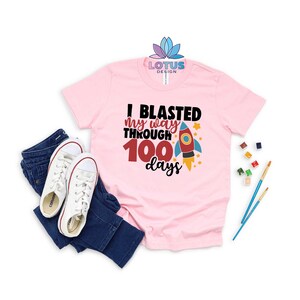 May include: Pink t-shirt with a rocket ship graphic and the text "I blasted my way through 100 days".