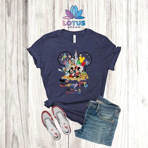 Puede incluir: Una camiseta azul marino con un gr&aacute;fico de Mickey Mouse y otros personajes de Disney. El texto "Disney Trip 2023" est&aacute; impreso debajo del gr&aacute;fico.