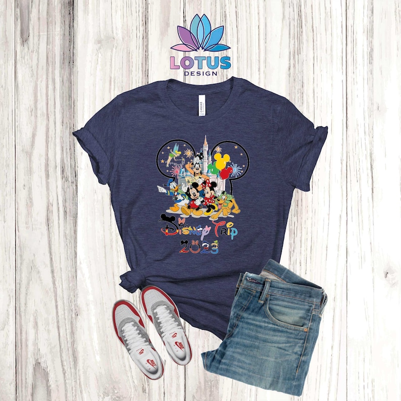 Puede incluir: Una camiseta azul marino con un gr&aacute;fico de Mickey Mouse y otros personajes de Disney. El texto "Disney Trip 2023" est&aacute; impreso debajo del gr&aacute;fico.