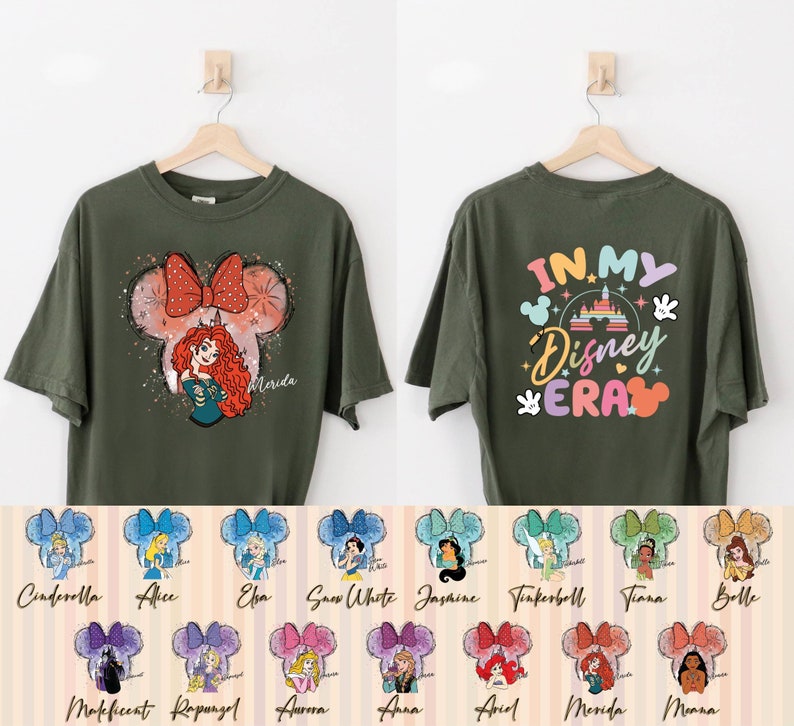 Puede incluir: Una camiseta verde con un gr&aacute;fico de una princesa de Disney con un lazo en la cabeza. La parte posterior de la camiseta dice "In My Disney Era" con un gr&aacute;fico del castillo de Disney. Hay 12 im&aacute;genes m&aacute;s peque&ntilde;as de diferentes princesas de Disney con lazos en la cabeza.